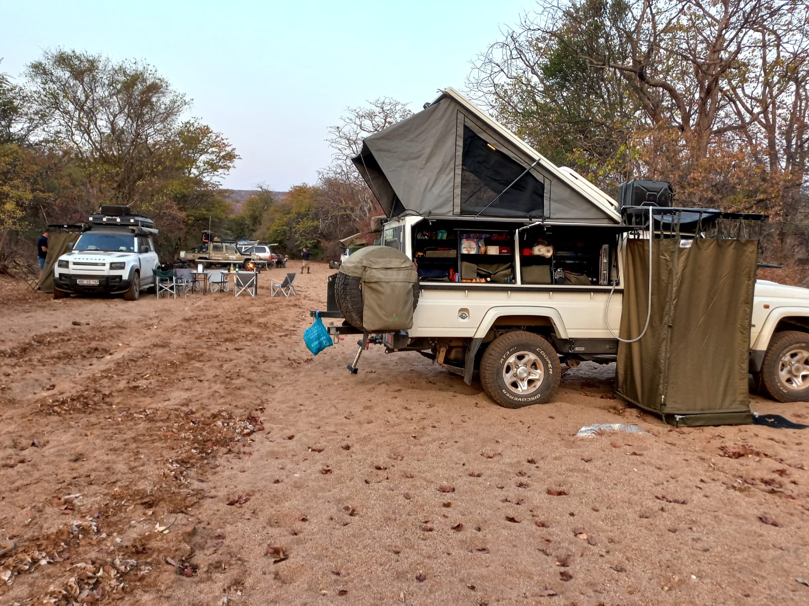 Rooftop tents and equipped 4×4 vehicles at a bush campsite.